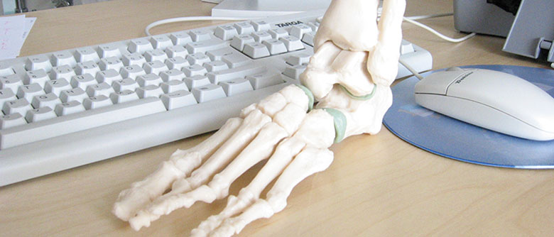 Computertastatur und anatomisches Fußmodell