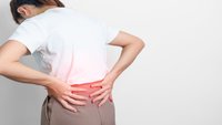 Orthopädiezentrum Wien - Iliopsoas-Verkuerzung bei einer Person, die ihren unteren Rücken hält