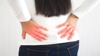 Orthopädiezentrum Wien - Frau hält sich das Iliosakralgelenk aufgrund von Schmerzen.