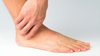 Orthopädiezentrum Wien - Eine Person hält sich das Sprunggelenk aufgrund von Beschwerden durch Osteochondrosis dissecans.