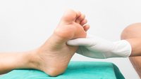 Orthopädiezentrum Wien - Eine Person in medizinischen Handschuhen untersucht den Fuß einer anderen Person wegen Charcot-Marie-Tooth