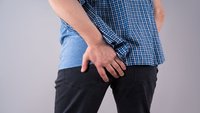 Orthopädiezentrum Wien - Coccygodynie (Steißbeinschmerzen) bei einer Person, die das Steißbein hält