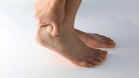 Orthopädiezentrum Wien - Eine Person greift sich an die Ferse aufgrund von Beschwerden durch einen Achillessehnenriss.