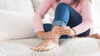 Orthopädiezentrum Wien - Eine Person greift sich den Unterschenkel aufgrund von Beschwerden durch Entzündung oder Riss der Tibialis-anterior-Sehne.