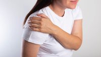 Orthopädiezentrum Wien - Frau hält sich die Schulter, möglicherweise aufgrund einer Schleimbeutelentzündung.