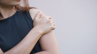 Orthopädiezentrum Wien - Frau hält sich die Schulter, was auf Beschwerden durch Schulterarthrose (Omarthrose) hindeuten könnte.