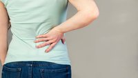 Orthopädiezentrum Wien - Glutealgie bei einer Person, die ihren unteren Rücken hält