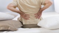 Orthopädiezentrum Wien - Eine ältere Person hält sich aufgrund eines Hexenschusses den unteren Rücken.